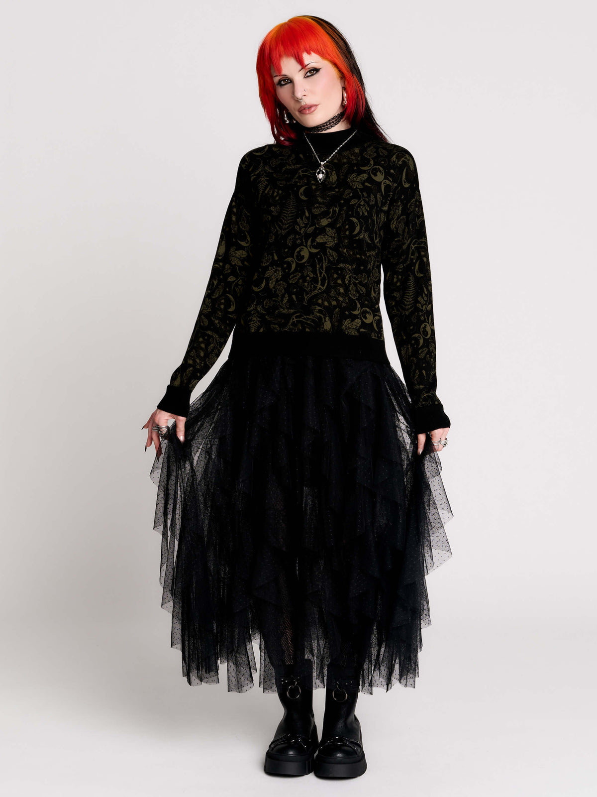 a black long-sleeve top with an intricate olive green forest findings pattern