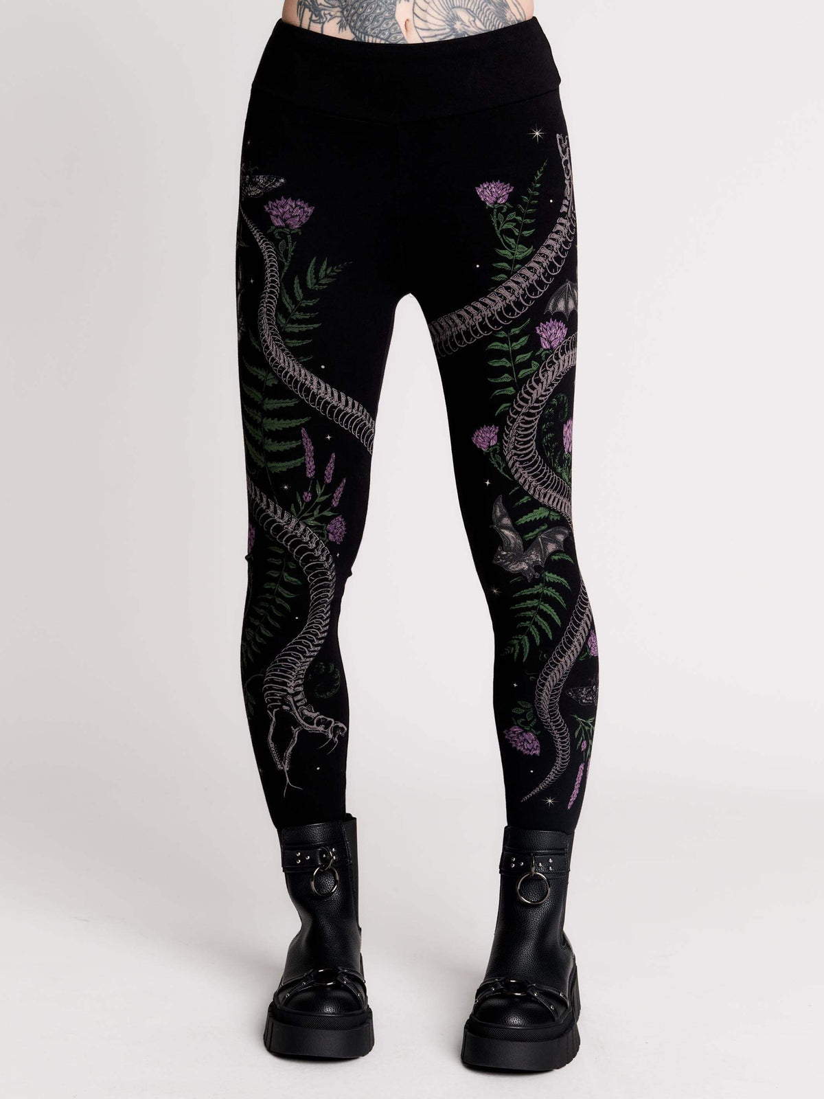 Black leggings with a detailed graphic print of a green fern, a purple flower, and a silver snake