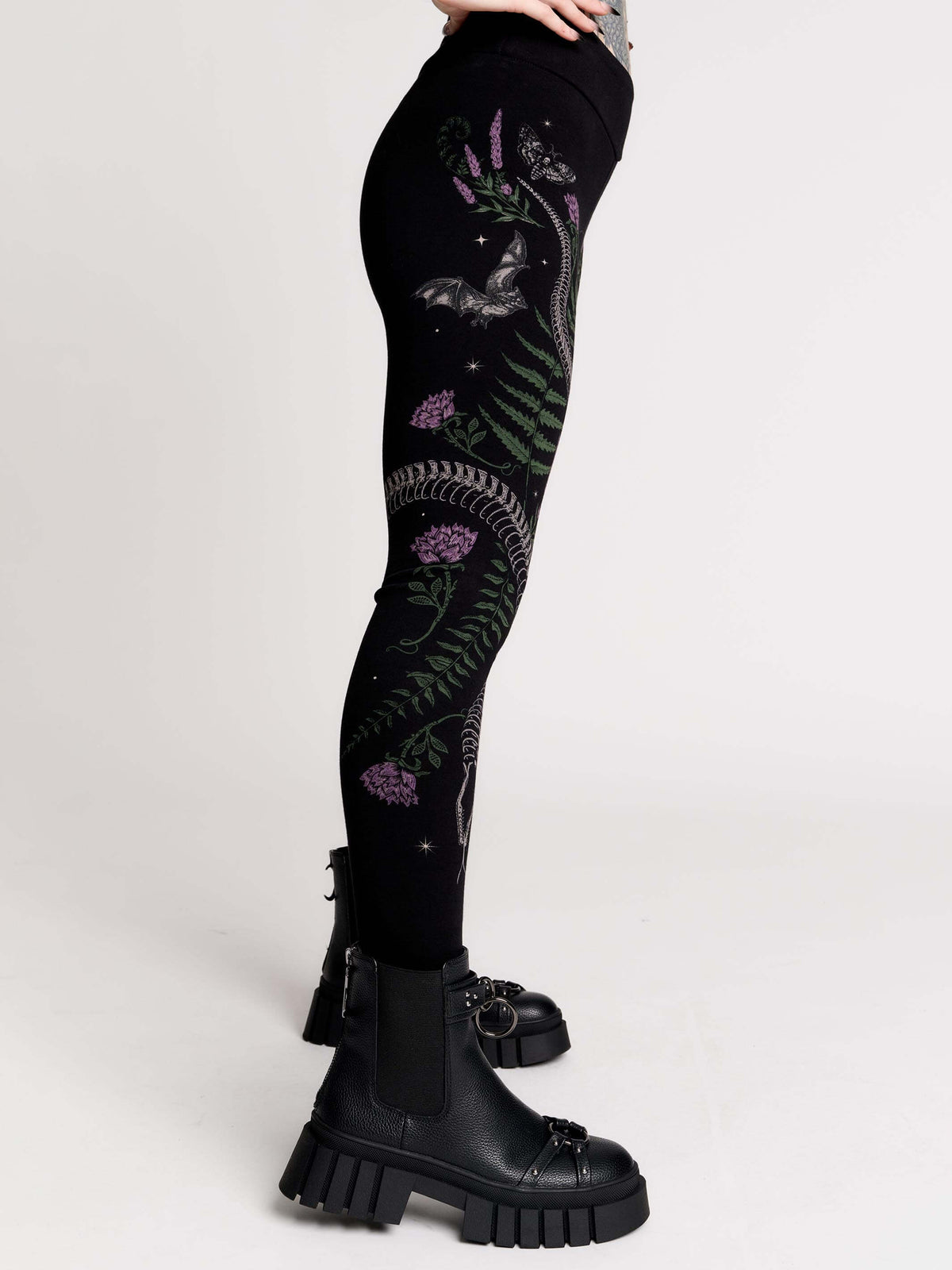 Black leggings with a detailed graphic print of a green fern, a purple flower, and a silver snake