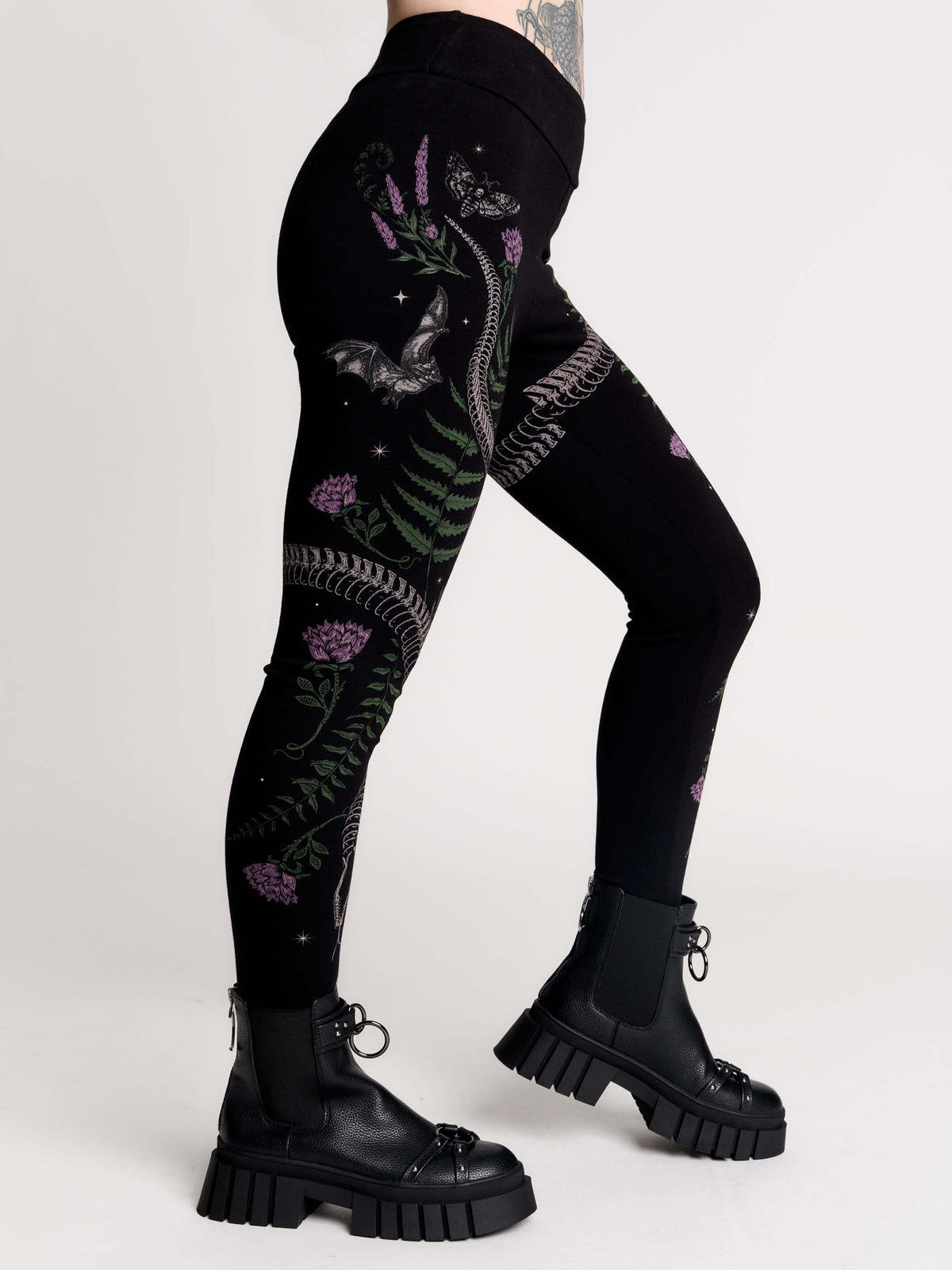 Black leggings with a detailed graphic print of a green fern, a purple flower, and a silver snake