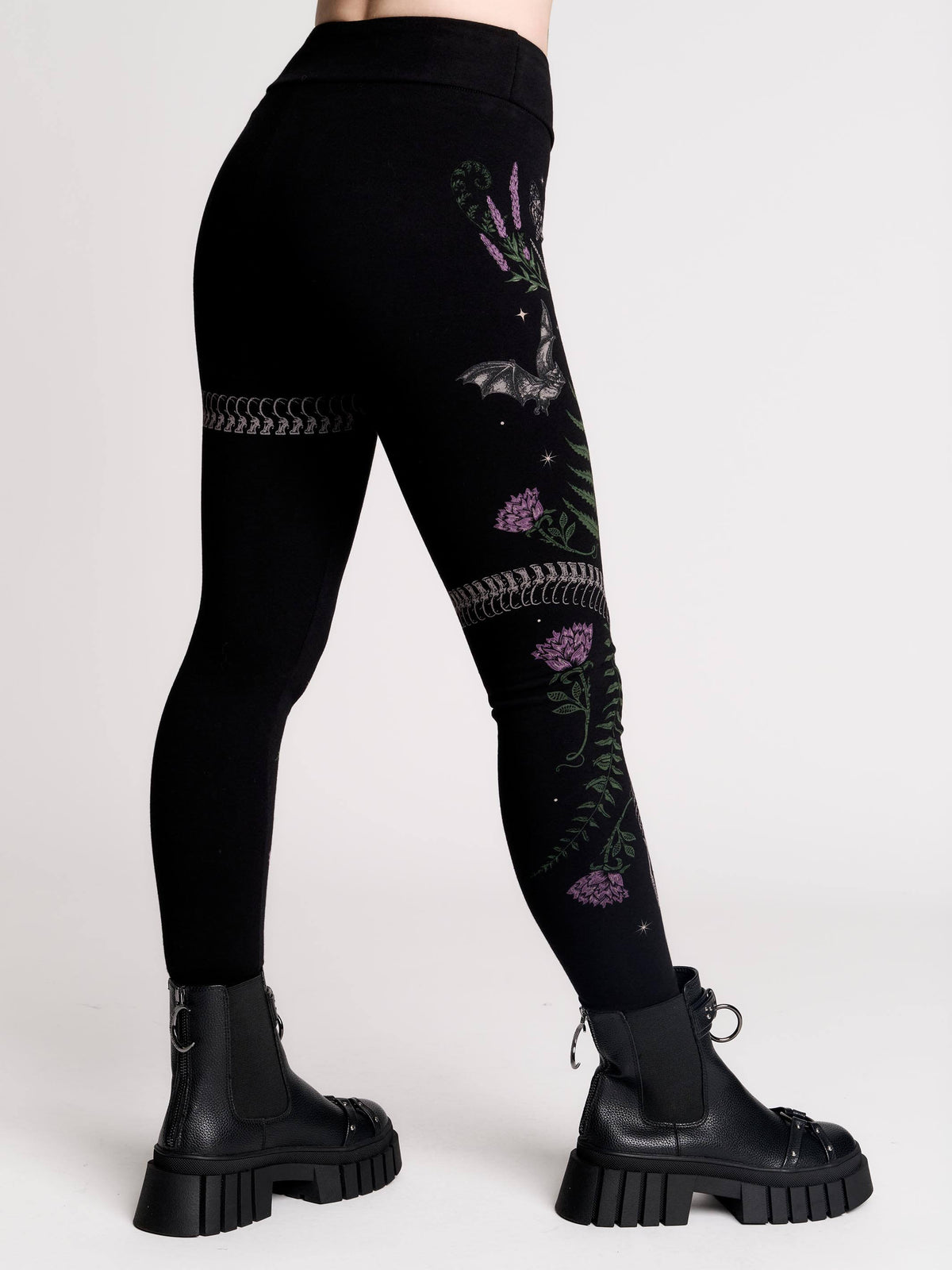 Black leggings with a detailed graphic print of a green fern, a purple flower, and a silver snake