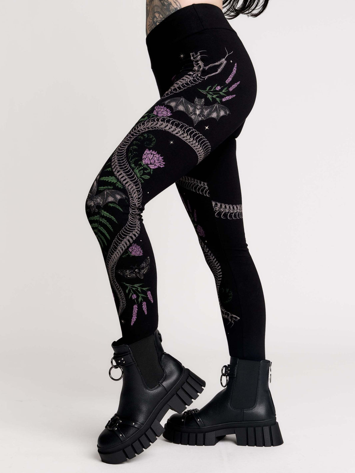 Black leggings with a detailed graphic print of a green fern, a purple flower, and a silver snake