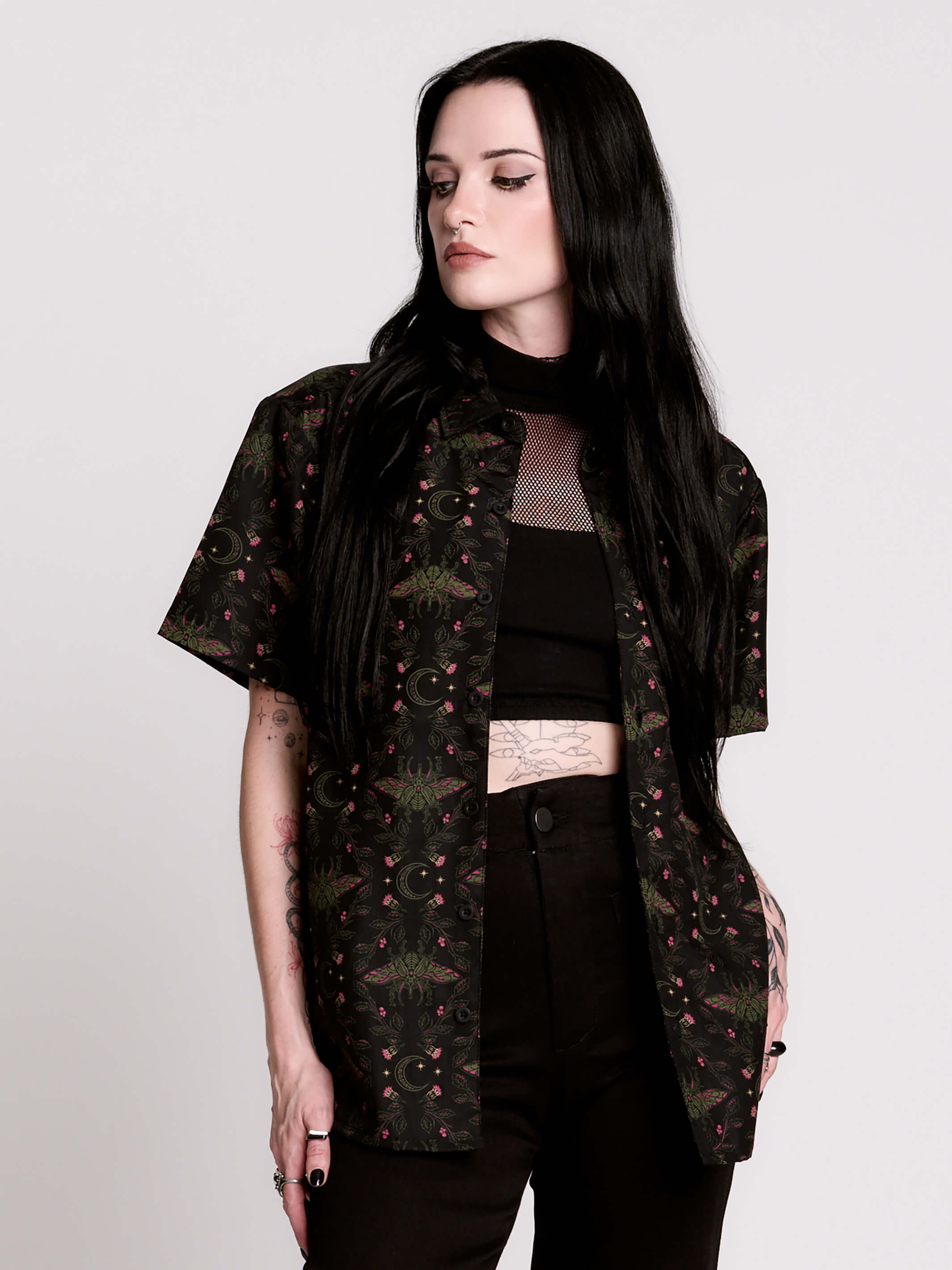 a black short-sleeve button-up shirt with a dark green and pink occult-style pattern.