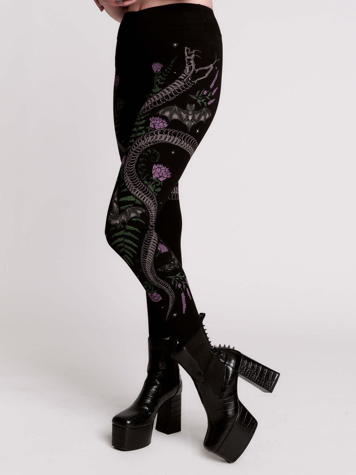 Black leggings with a detailed graphic print of a green fern, a purple flower, and a silver snake