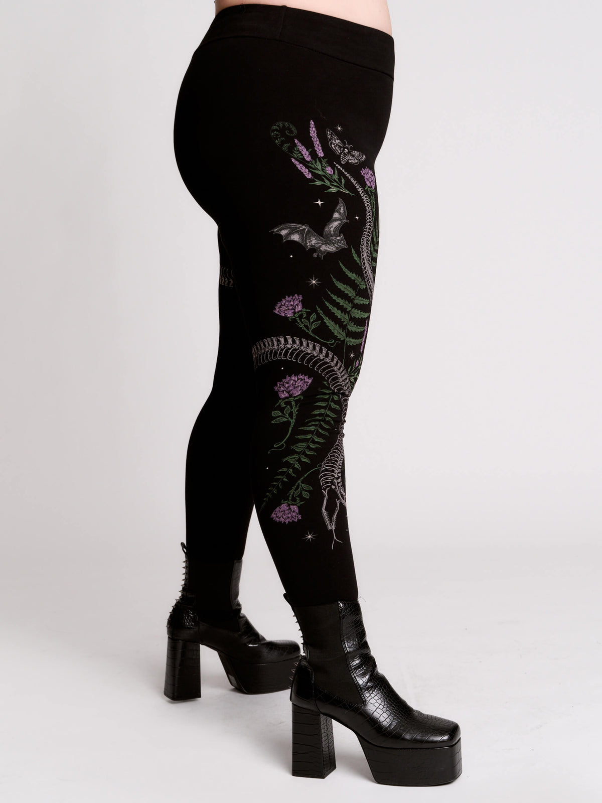 Black leggings with a detailed graphic print of a green fern, a purple flower, and a silver snake