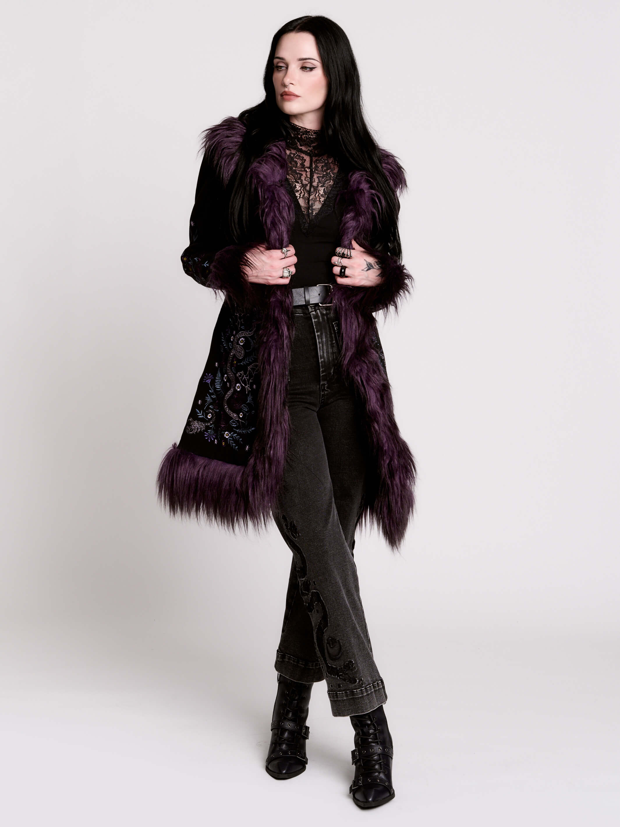This mid-length black coat pairs a soft, suede-like finish with plush amethyst-purple faux fur trim