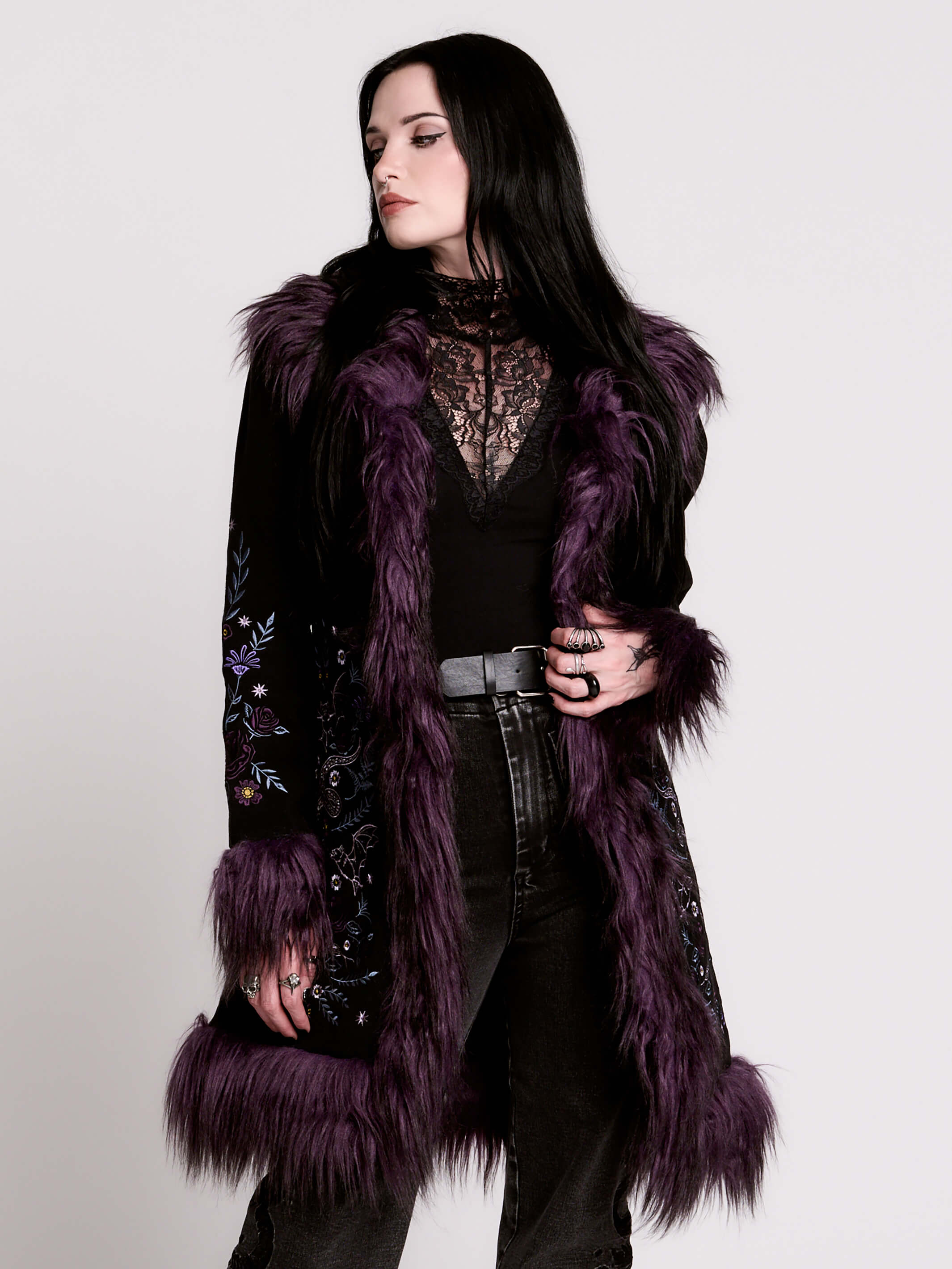 This mid-length black coat pairs a soft, suede-like finish with plush amethyst-purple faux fur trim