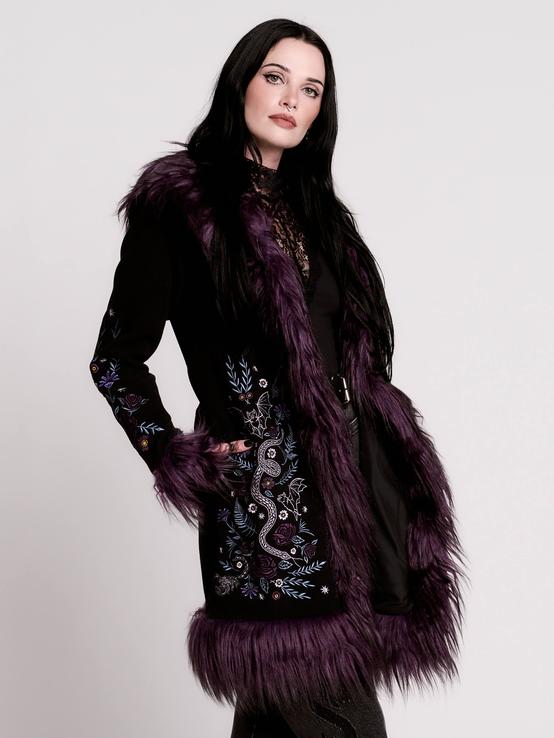 This mid-length black coat pairs a soft, suede-like finish with plush amethyst-purple faux fur trim