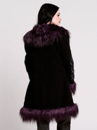 This mid-length black coat pairs a soft, suede-like finish with plush amethyst-purple faux fur trim
