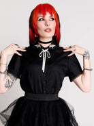 black short-sleeve blouse with white embroidered bat on collar and black lace trim