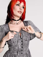 a gray and black patterned dress with black lace trim and buttons.