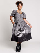 short-sleeved gray and black gothic-style midi dress with a printed illustration of a woman and winged figure at the hem