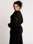a black long-sleeve top with an intricate olive green forest findings pattern