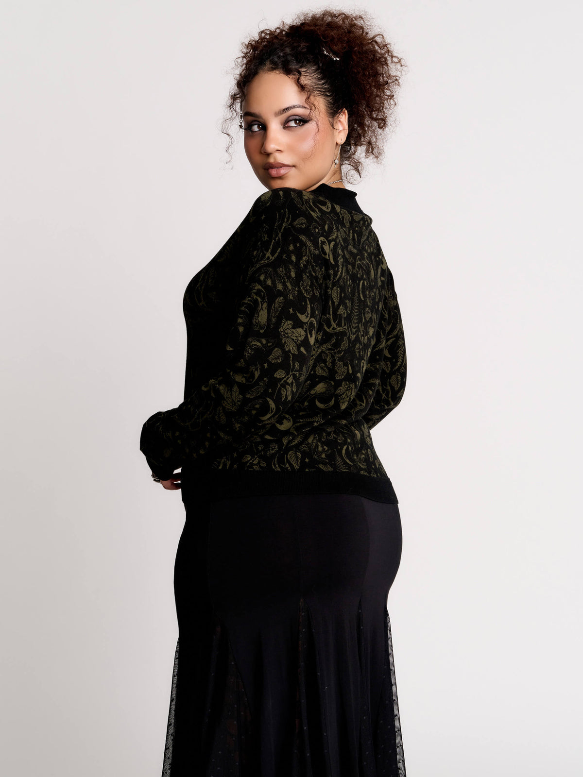 a black long-sleeve top with an intricate olive green forest findings pattern