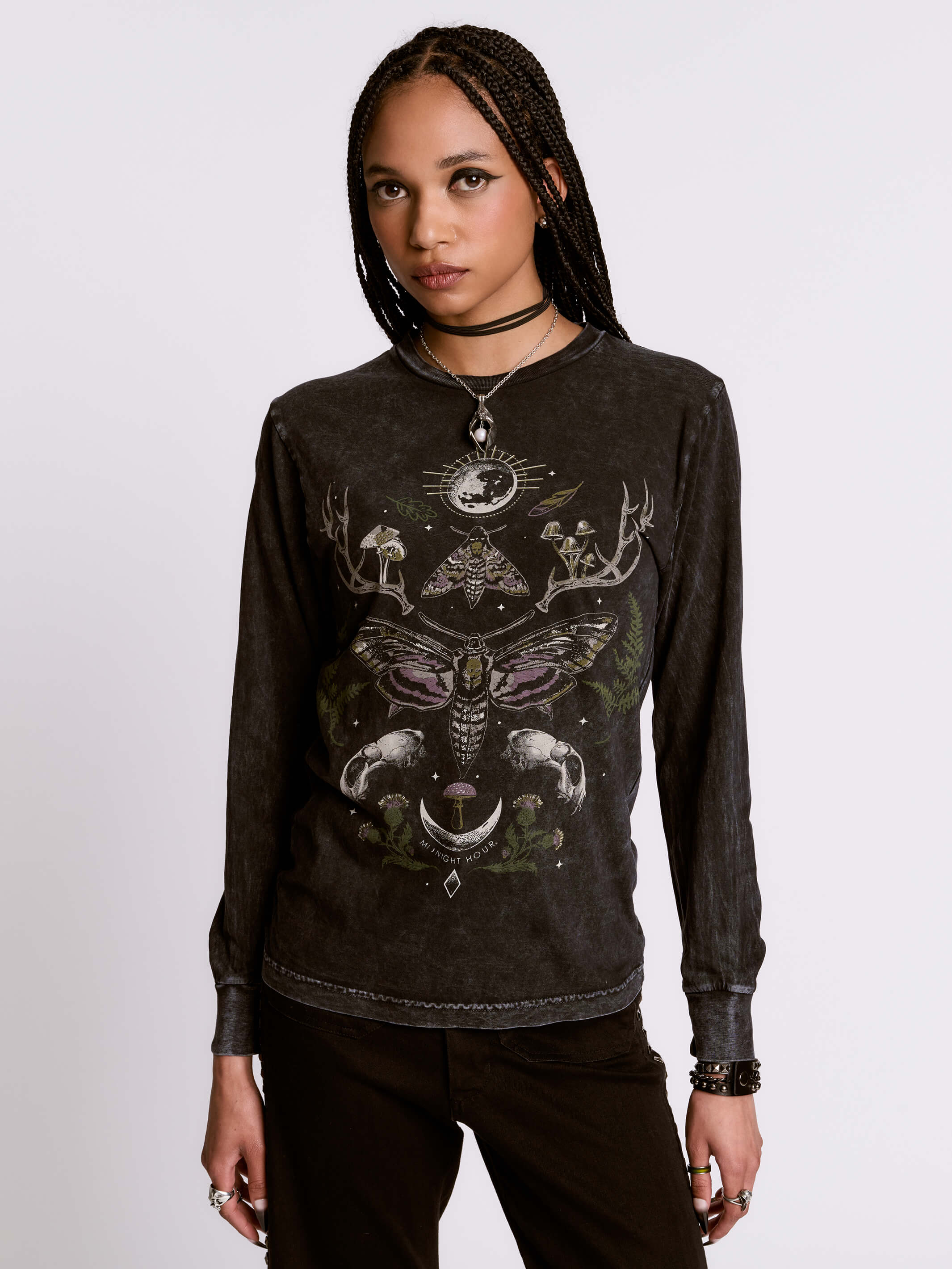 Person wearing a black long-sleeve shirt with intricate designs on a plain background