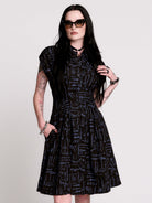 a button-front shirt dress featuring a striking medieval-inspired print with weaponry and macabre motifs. 
