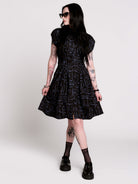 a button-front shirt dress featuring a striking medieval-inspired print with weaponry and macabre motifs. 