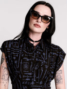 a button-front shirt dress featuring a striking medieval-inspired print with weaponry and macabre motifs. 