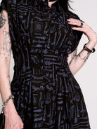 a button-front shirt dress featuring a striking medieval-inspired print with weaponry and macabre motifs. 