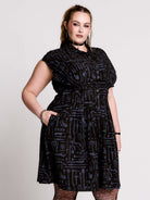 a button-front shirt dress featuring a striking medieval-inspired print with weaponry and macabre motifs. 