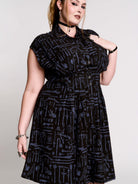 a button-front shirt dress featuring a striking medieval-inspired print with weaponry and macabre motifs. 