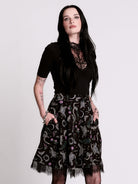 A  black flared skirt featuring a gray and purple gothic print with lace hem.