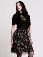 A  black flared skirt featuring a gray and purple gothic print with lace hem.