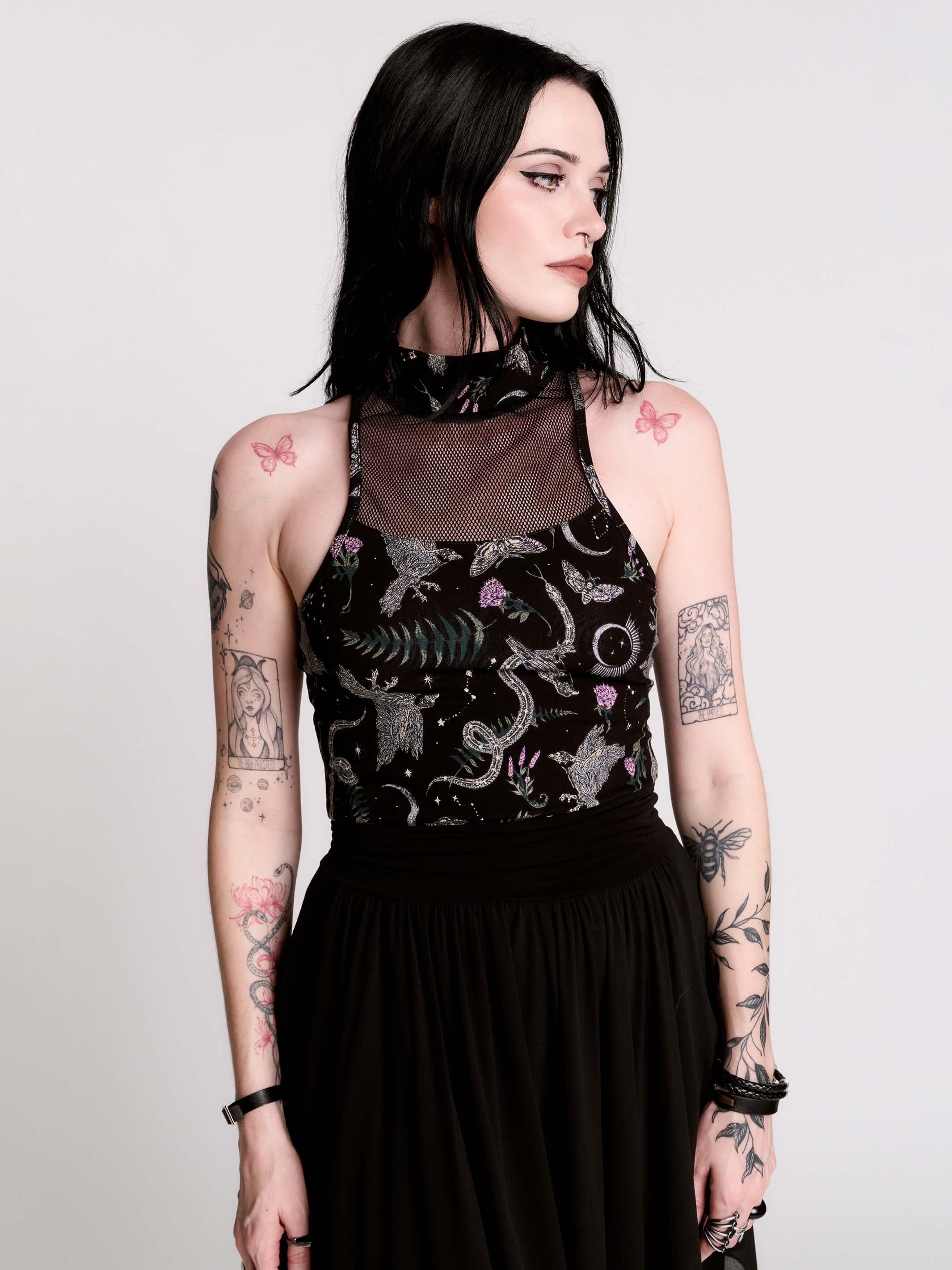 A black sleeveless top with a high mesh neck and an allover gothic-style print featuring silver snakes, moths, ravens and small pink floral accents.