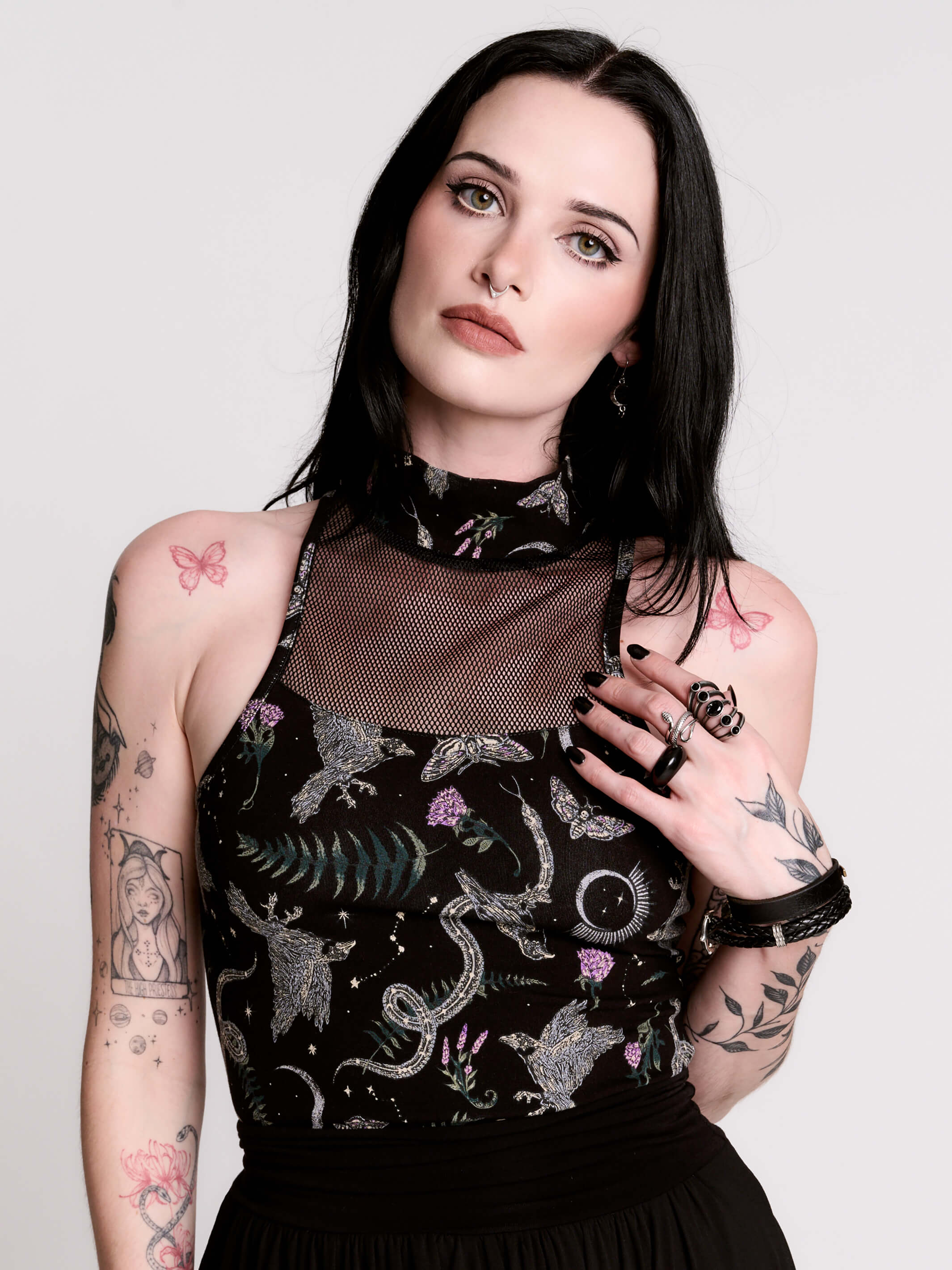 A black sleeveless top with a high mesh neck and an allover gothic-style print featuring silver snakes, moths, ravens and small pink floral accents.