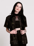 a black short-sleeve button-up shirt with a dark green and pink occult-style pattern.