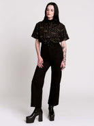 a black short-sleeve button-up shirt with a dark green and pink occult-style pattern.