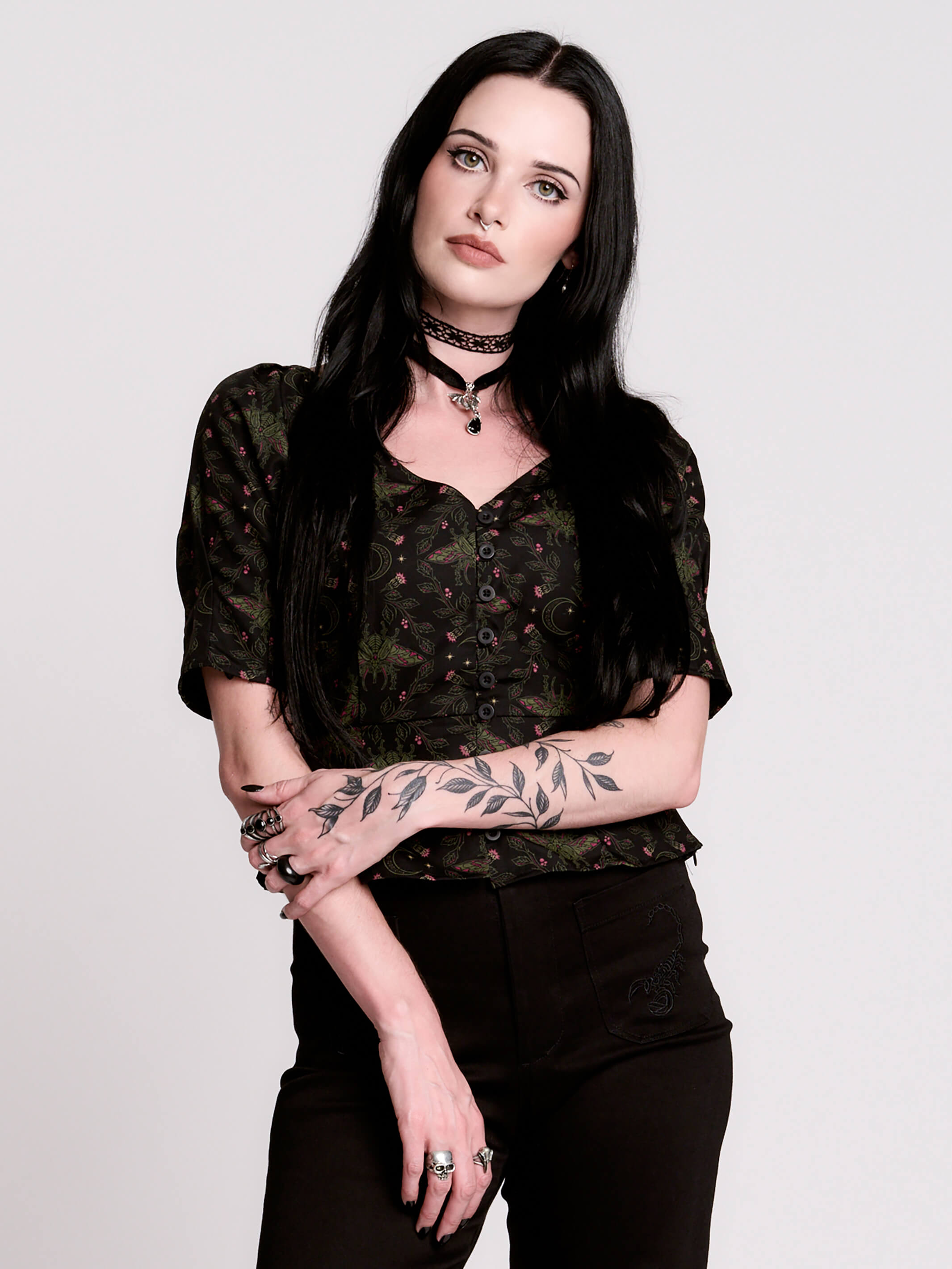A short-sleeve button-up blouse featuring a dark green and black gothic pattern with pink accents.