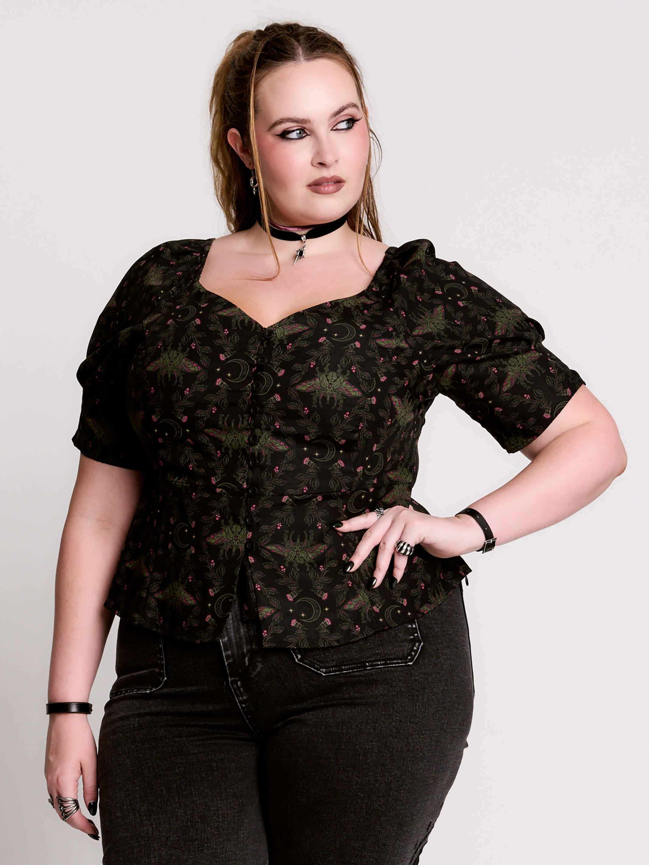 A short-sleeve button-up blouse featuring a dark green and black gothic pattern with pink accents.