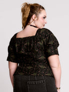 A short-sleeve button-up blouse featuring a dark green and black gothic pattern with pink accents.