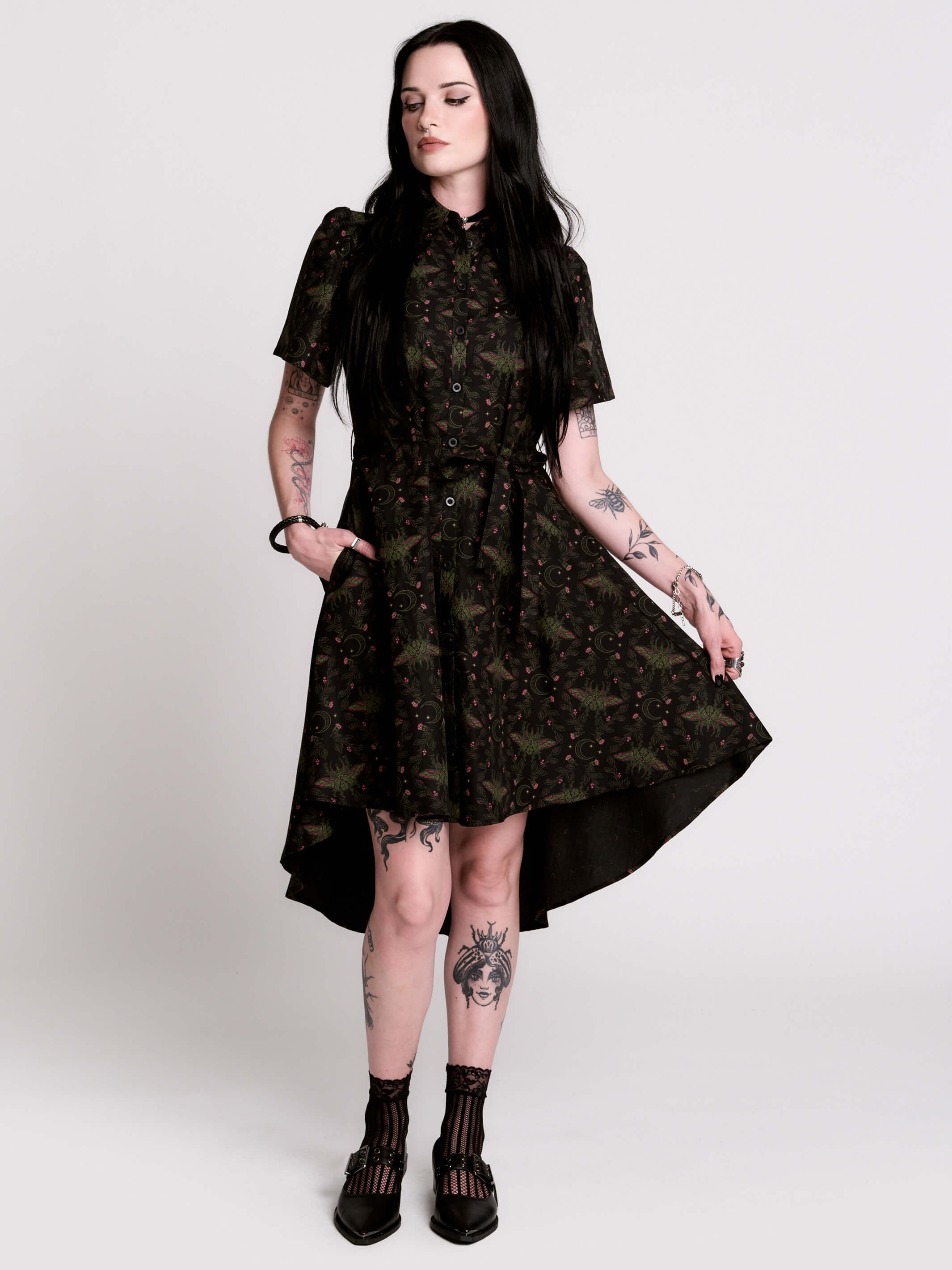a short-sleeved high-low dress in black with a small red and green floral pattern.