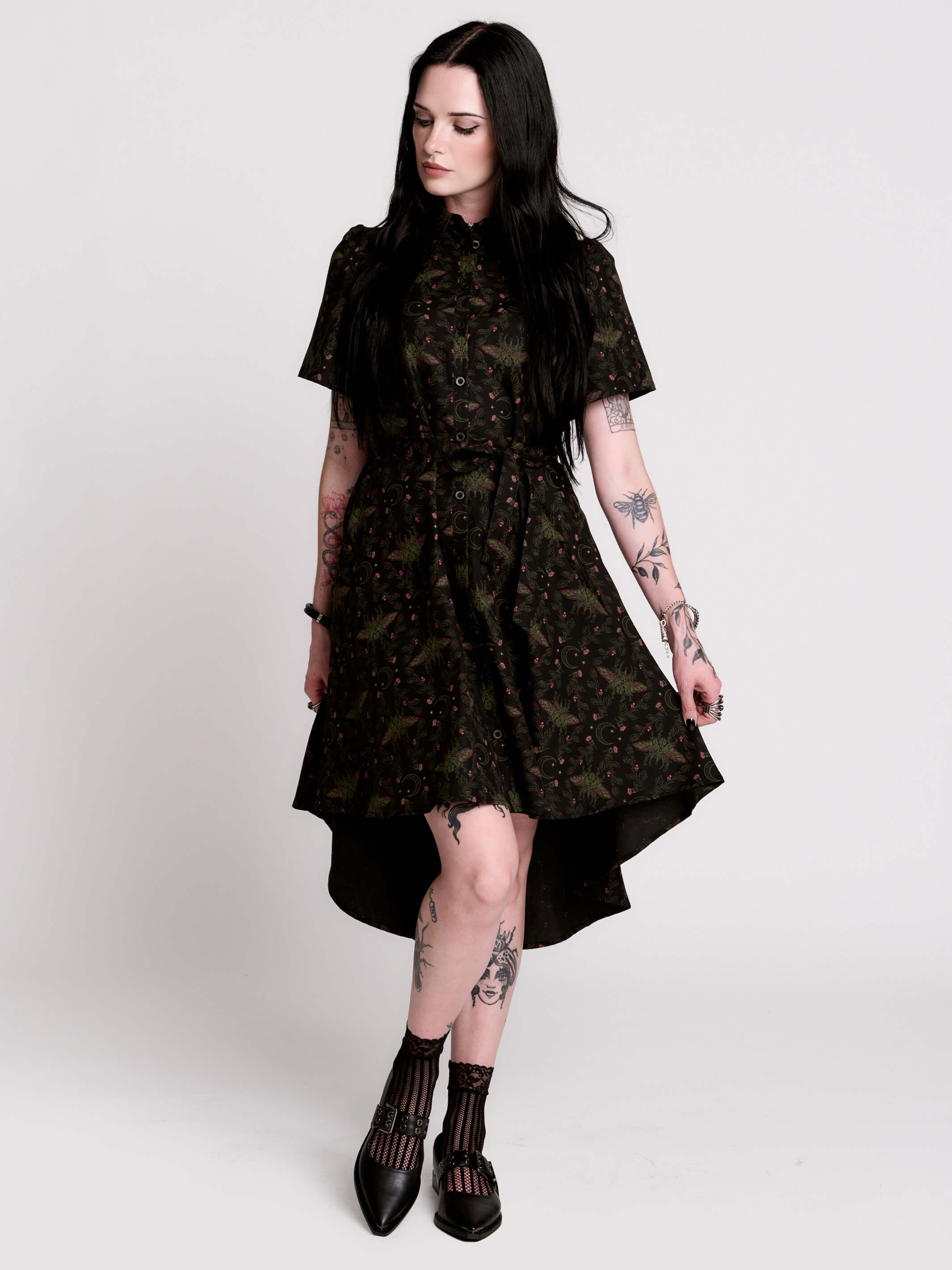 a short-sleeved high-low dress in black with a small red and green floral pattern.
