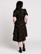 a short-sleeved high-low dress in black with a small red and green floral pattern.