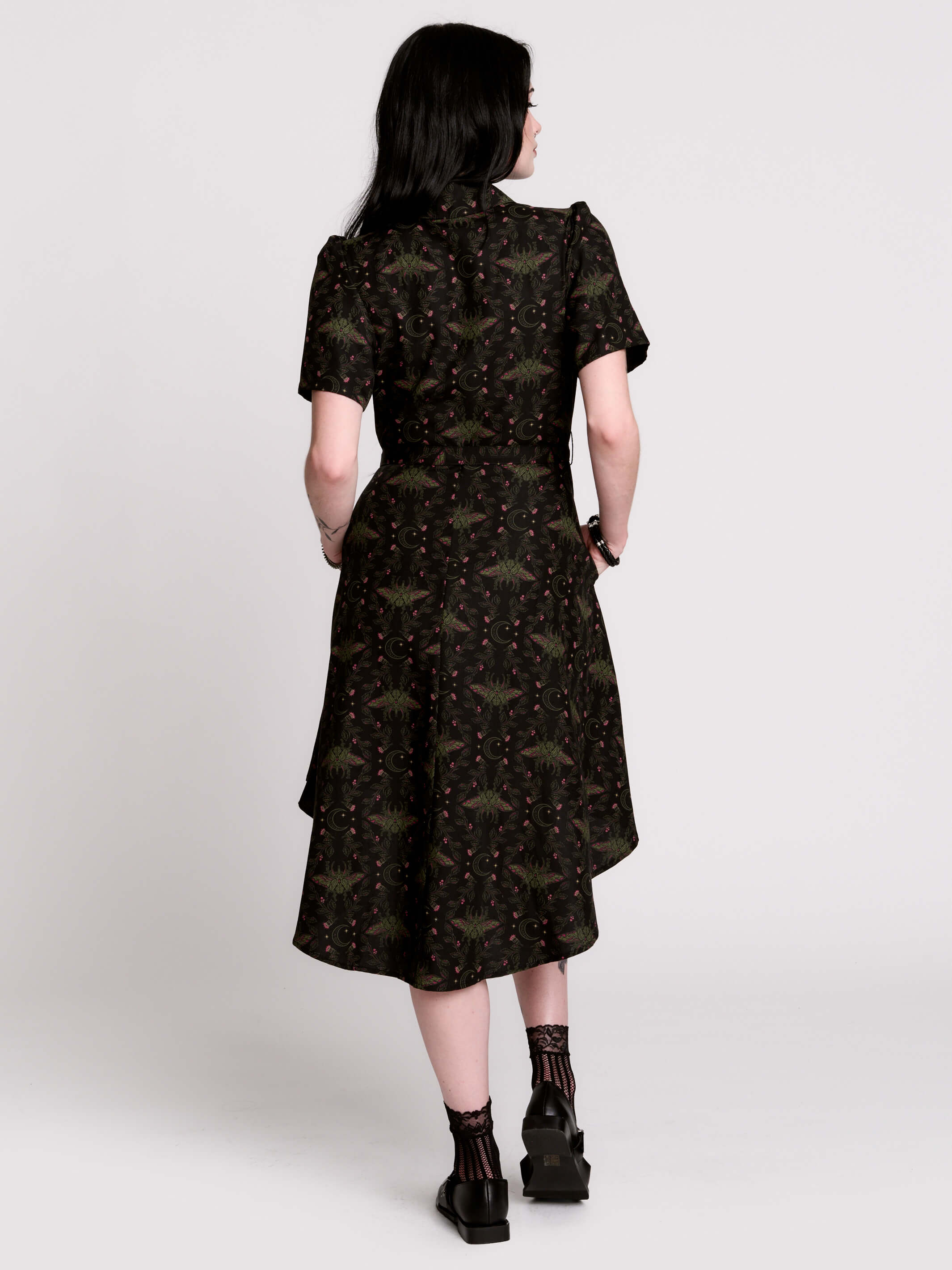 a short-sleeved high-low dress in black with a small red and green floral pattern.