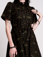 a short-sleeved high-low dress in black with a small red and green floral pattern.