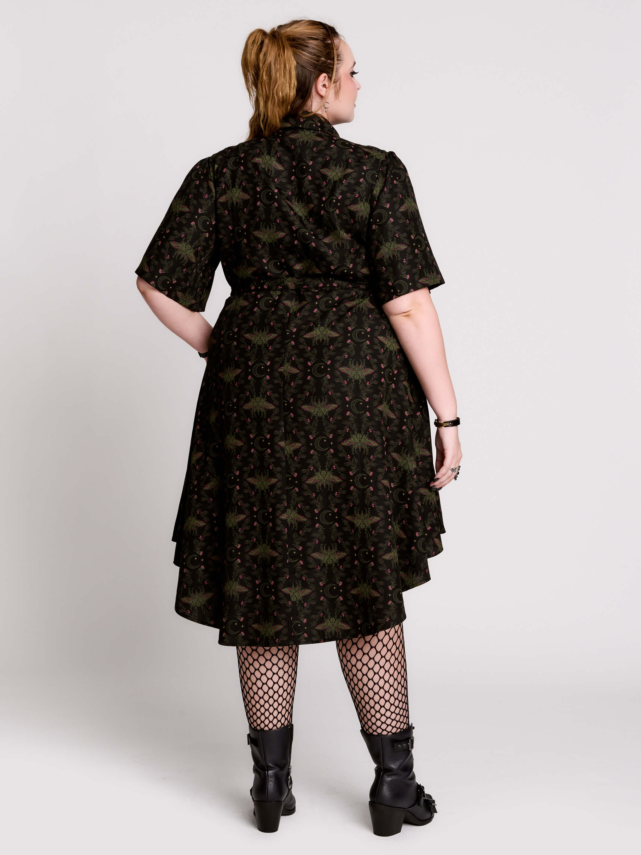 a short-sleeved high-low dress in black with a small red and green floral pattern.