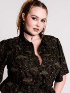 a short-sleeved high-low dress in black with a small red and green floral pattern.