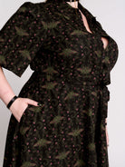 a short-sleeved high-low dress in black with a small red and green floral pattern.